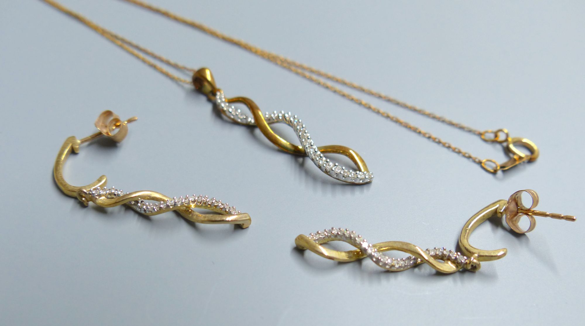 A modern 10kt and diamond chip set spiral pendant, 30mm, on a 10kt fine link chain, 45mm and pair of matching earrings,
